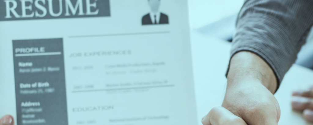 A la imatge es veu un Curriculum Vitaé i dues persones donan't-se les mans, formalitzant una contractació.